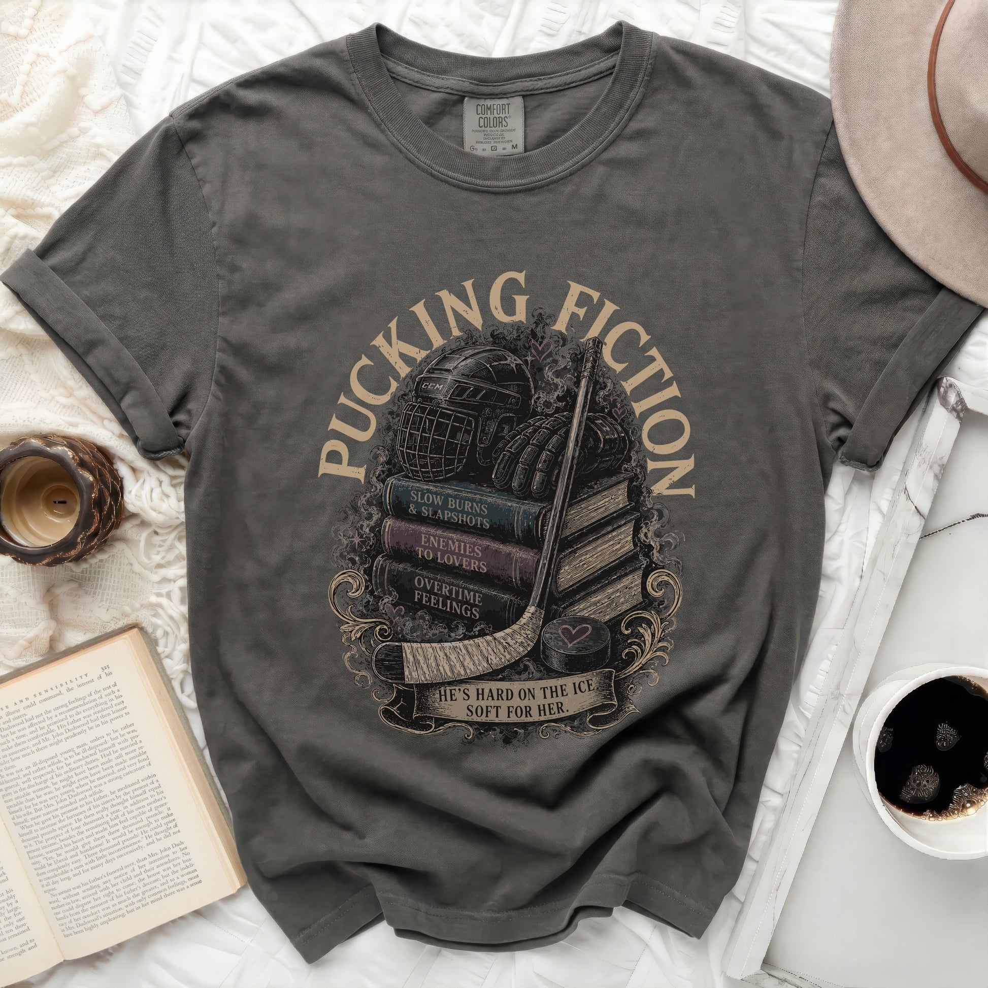 Dark gray t-shirt with stacked books, hockey gear, and "Pucking Fiction" text.