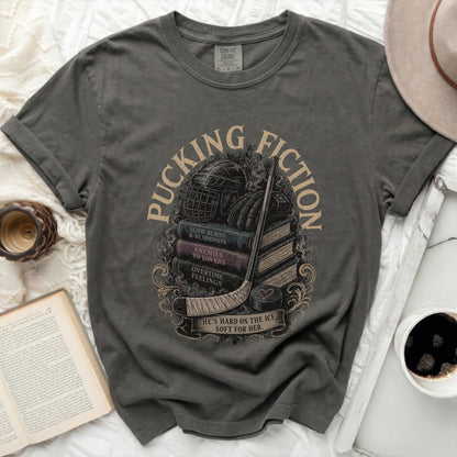 Dark gray t-shirt with stacked books, hockey gear, and "Pucking Fiction" text.