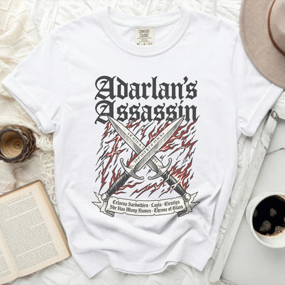 White t-shirt with "Adarlan's Assassin" and crossed swords graphic.