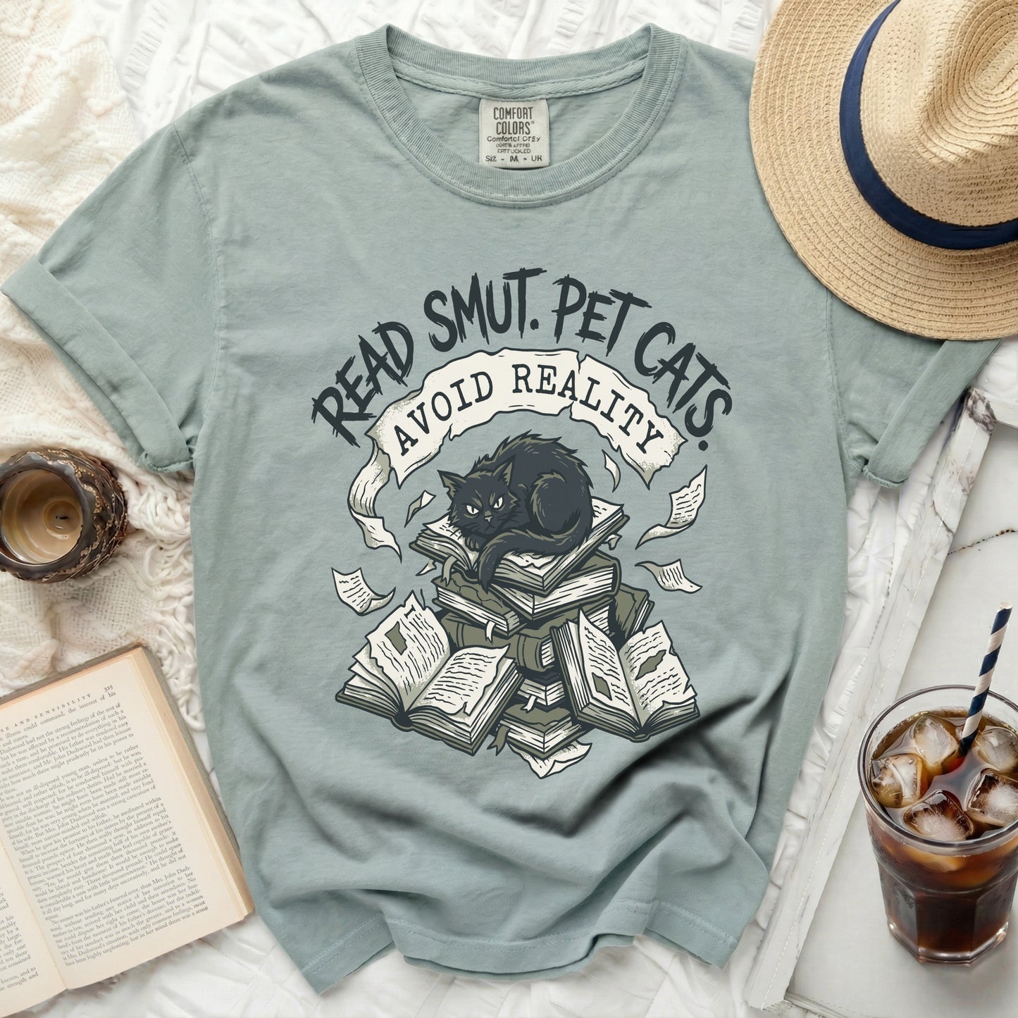 T-shirt with black cat on books, "Read Smut. Pet Cats. Avoid Reality." text.