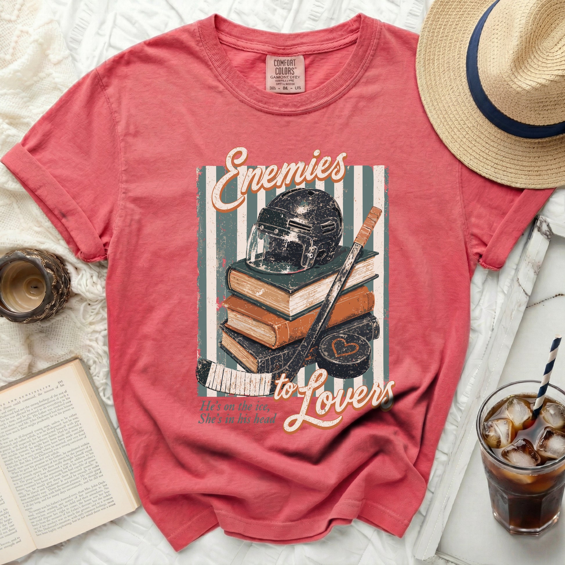 Red t-shirt graphic: hockey helmet, puck, stick, and books with "Enemies to Lovers" text.