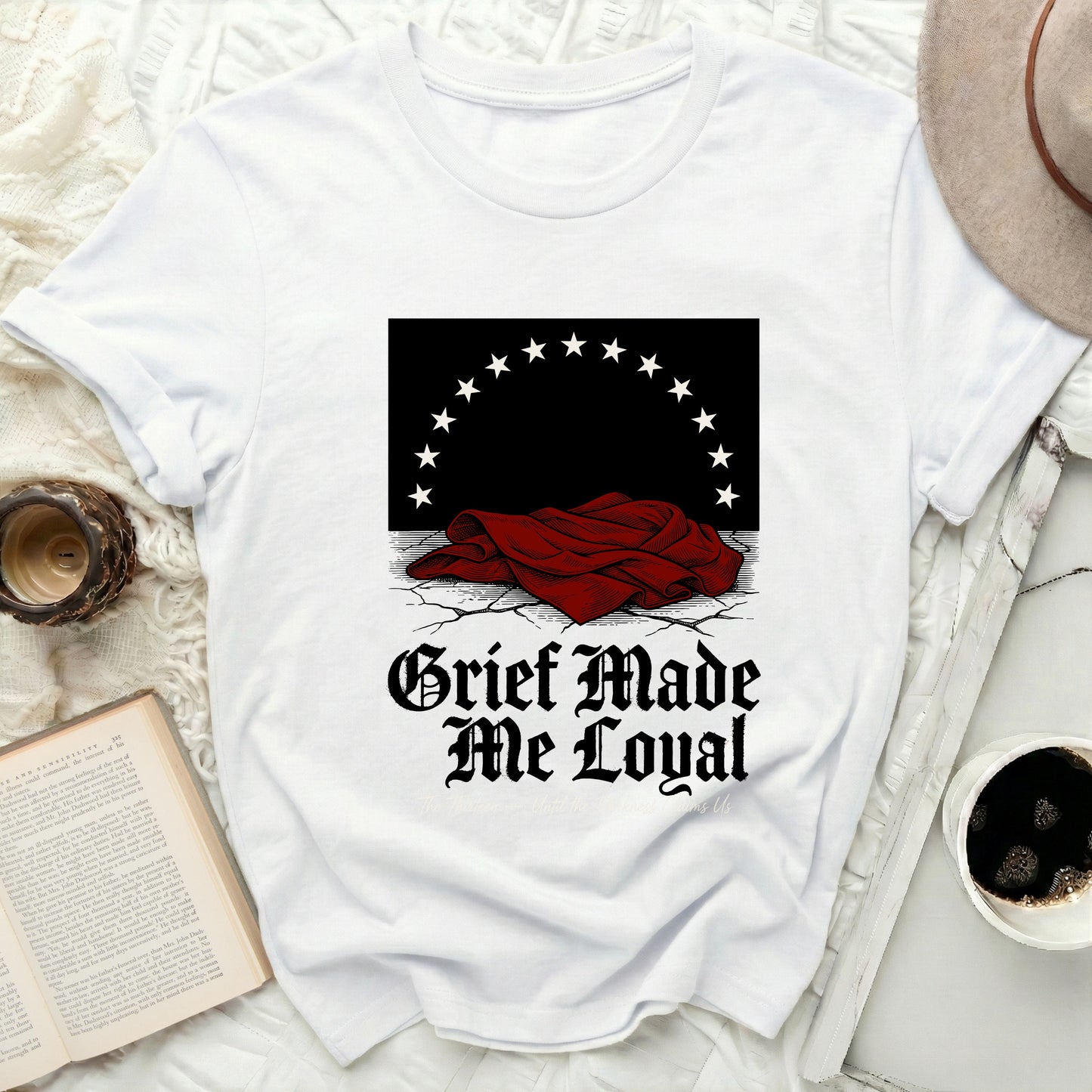 White t-shirt with "Grief Made Me Loyal" text and black star design.