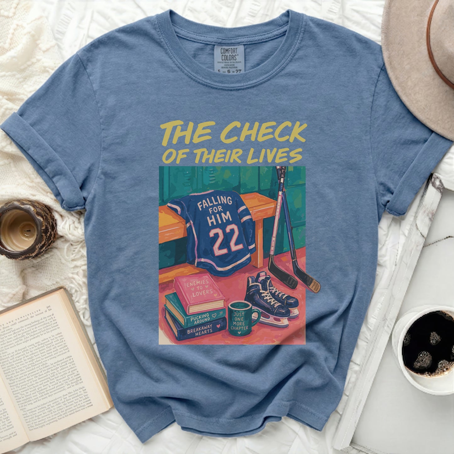 Blue Comfort Colors t-shirt with falling dominoes, hockey gear, and books.