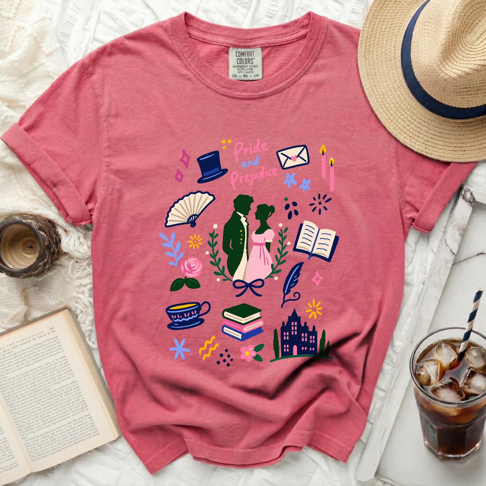 Pink t-shirt with Pride and Prejudice literary graphic and accessories, including a straw hat.