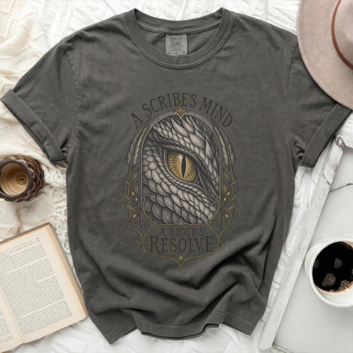 A dark gray t-shirt with a dragon eye graphic and the text A Scribe's Mind, A Rider's Resolve.