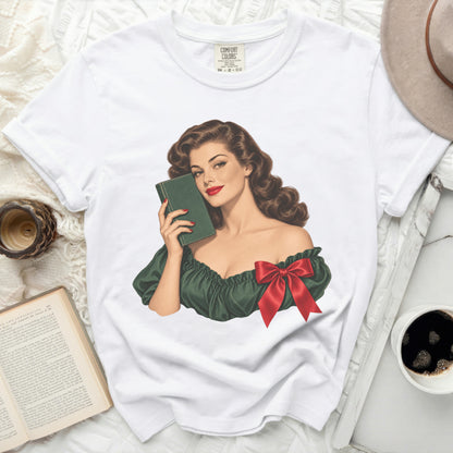 White t-shirt with vintage pin-up style illustration of woman holding a green book and red bow.