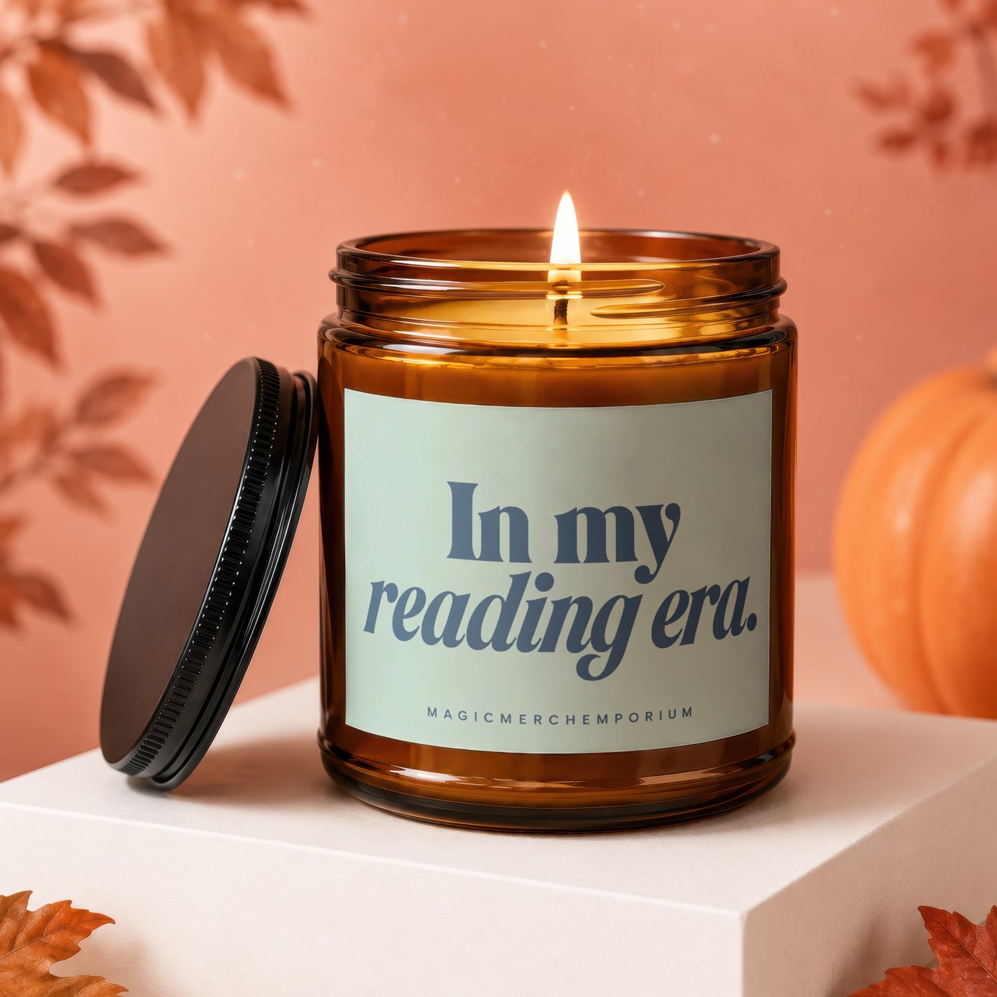 Amber jar candle with lit flame, lid askew, reading "In my reading era."