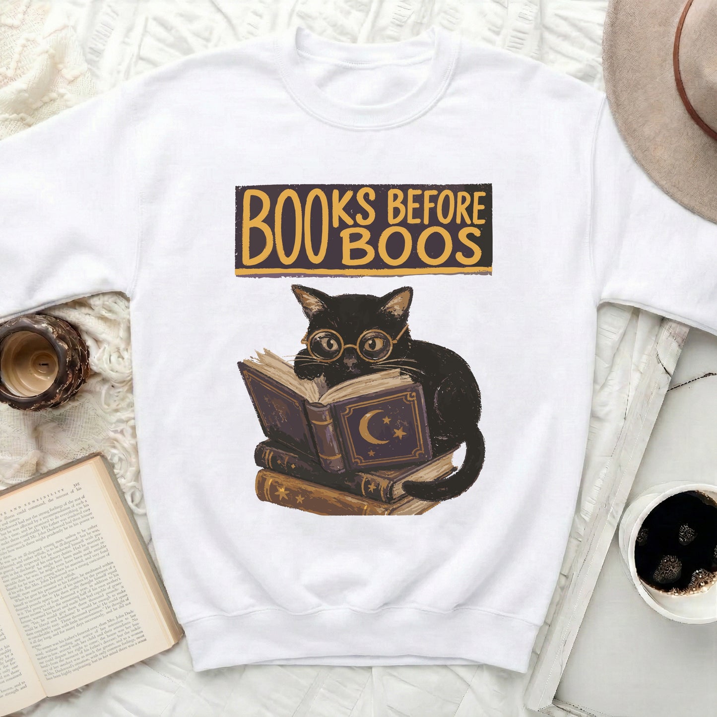 Black cat wearing spectacles sits on books with "BOOKS BEFORE BOOS" text.