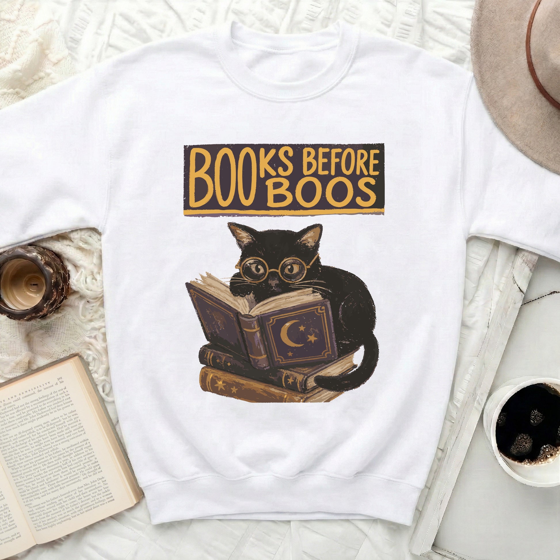Black cat wearing spectacles sits on books with "BOOKS BEFORE BOOS" text.