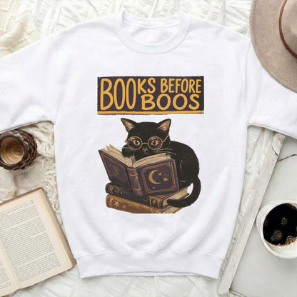Black cat wearing spectacles sits on books with "BOOKS BEFORE BOOS" text.