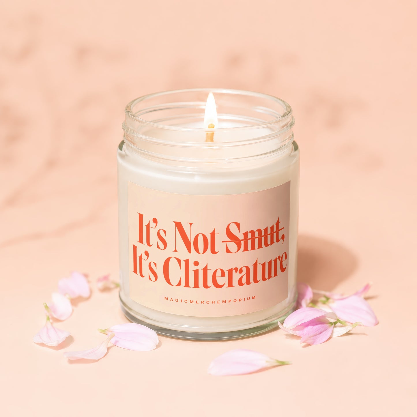 Candle with text "It's Not Smut, It's Cliterature" surrounded by pink flower petals.