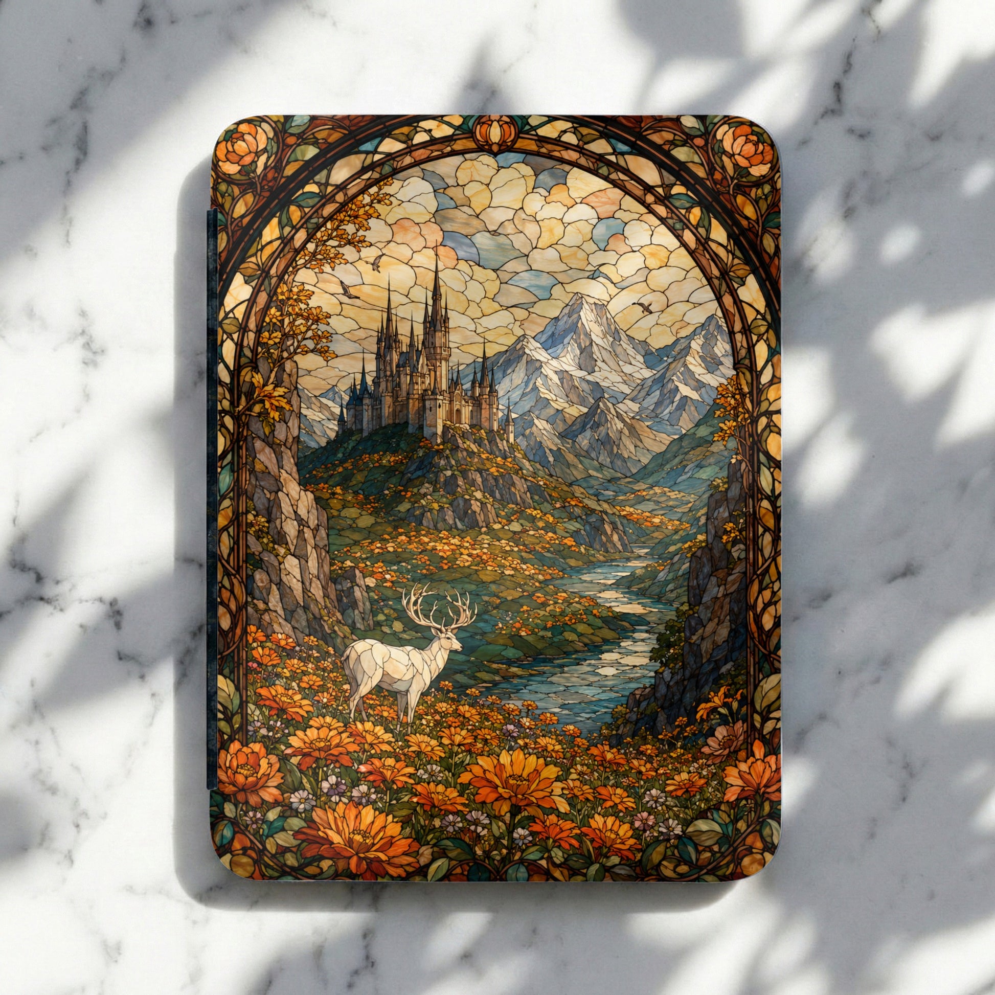 Stained glass art of a white stag in a field of orange flowers with a castle and mountains.