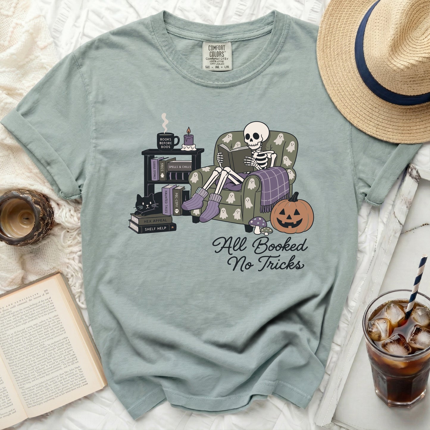 Skeleton reading "All Booked No Tricks" on a sage green shirt.