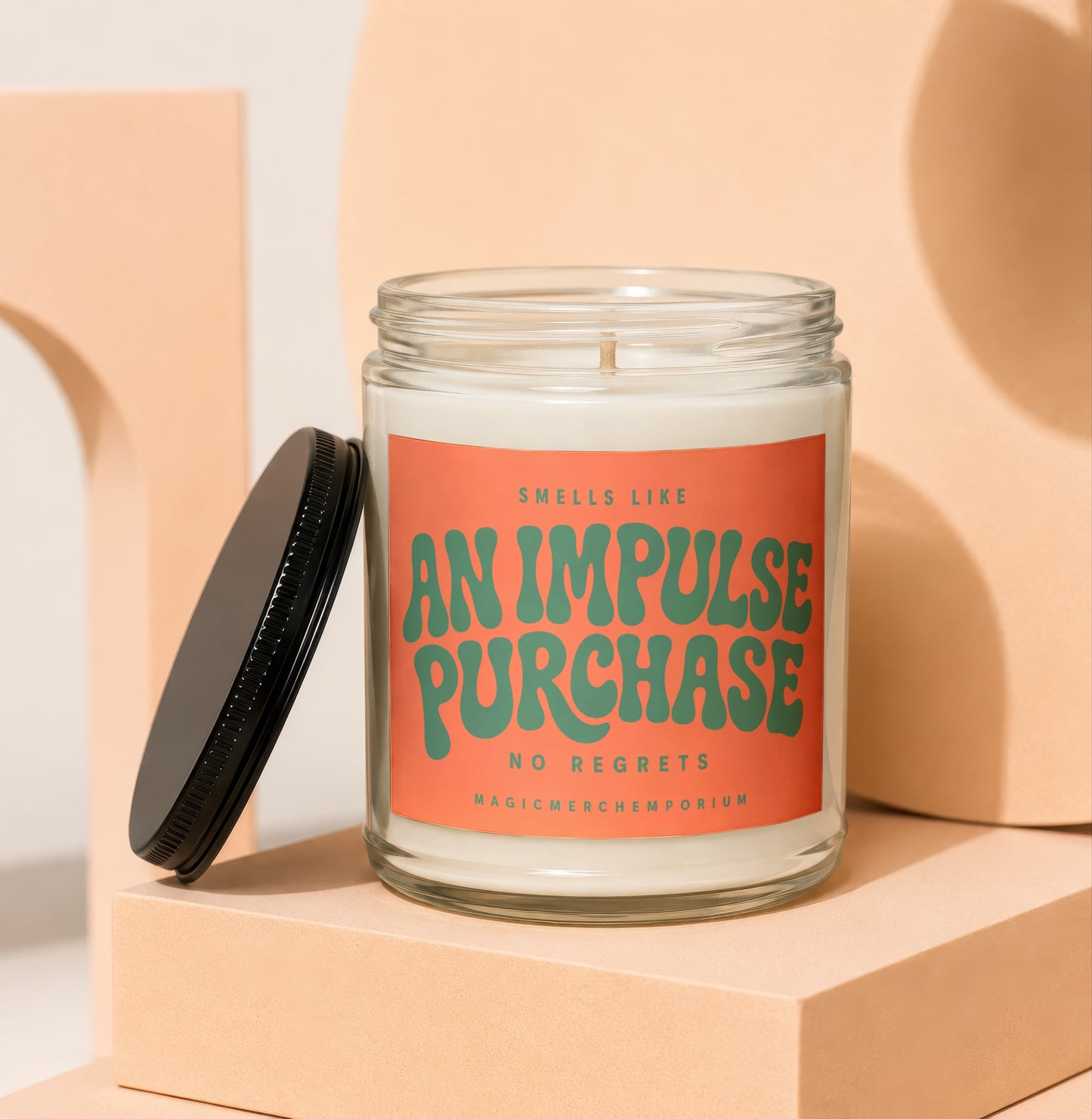Candle with orange label reading "SMells like AN IMPULSE PURCHASE NO REGRETS MAGICMERCHEMPORIUM".