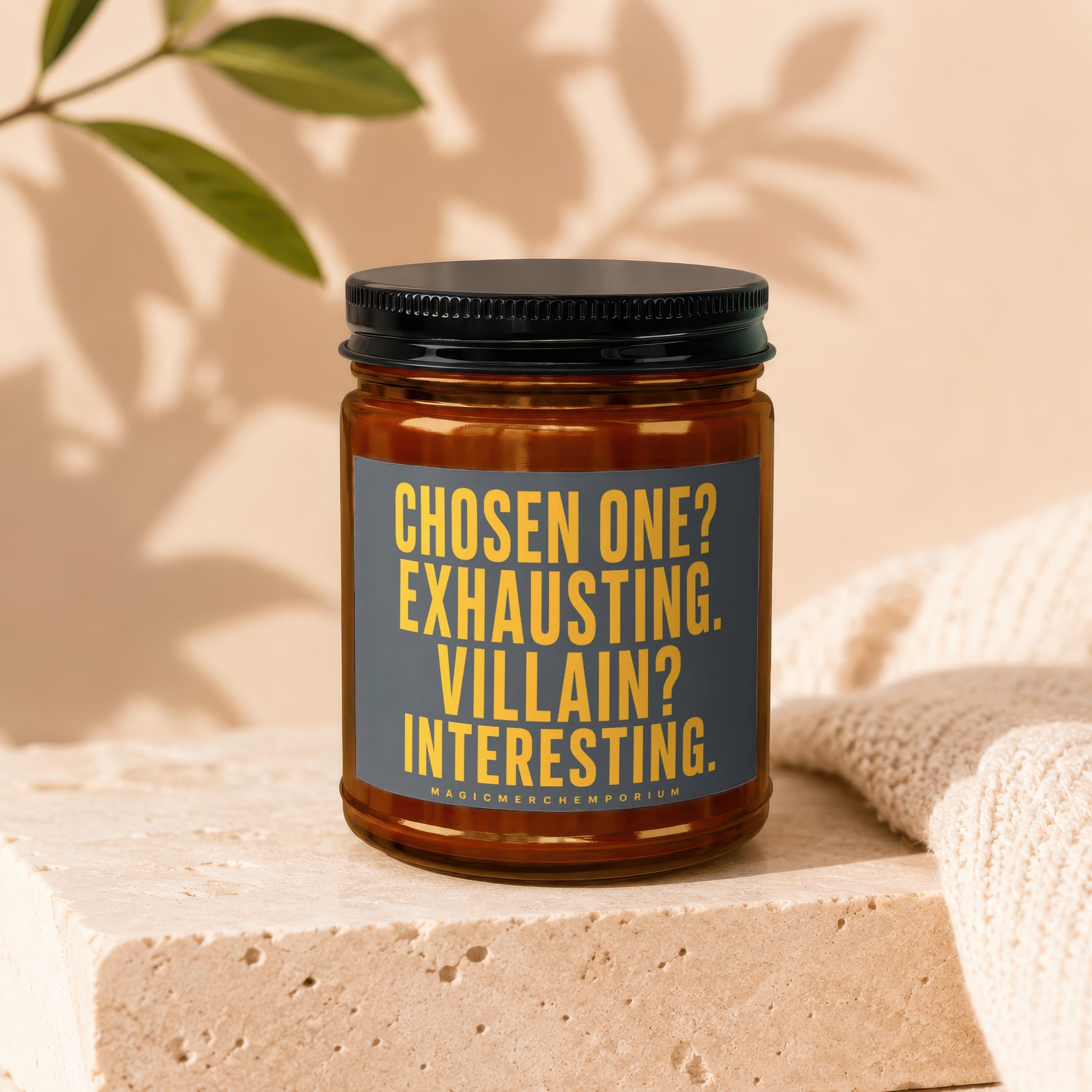 Amber candle with a black lid, featuring a dark gray label with yellow text.
