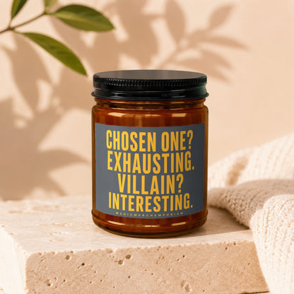 Amber candle with a black lid, featuring a dark gray label with yellow text.