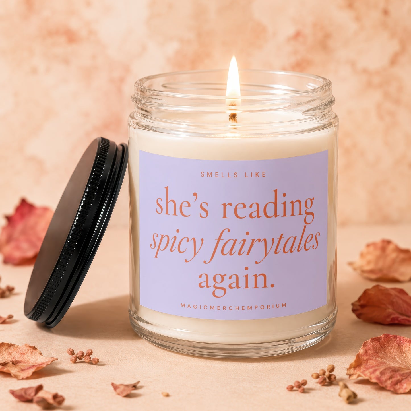 Candle with lit wick and label reading "smells like she's reading spicy fairytales again."