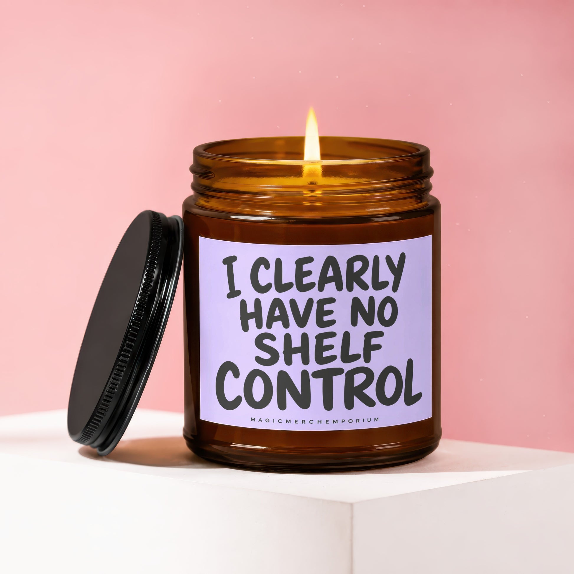 Amber glass candle with lit flame and label reading "I CLEARLY HAVE NO SHELF CONTROL."