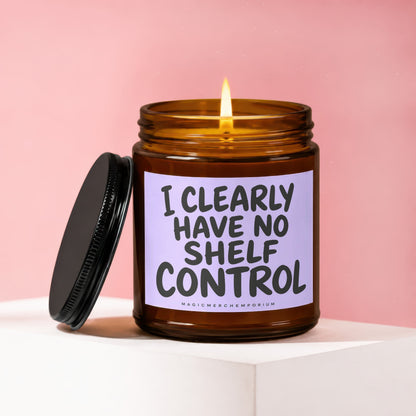Amber glass candle with lit flame and label reading "I CLEARLY HAVE NO SHELF CONTROL."