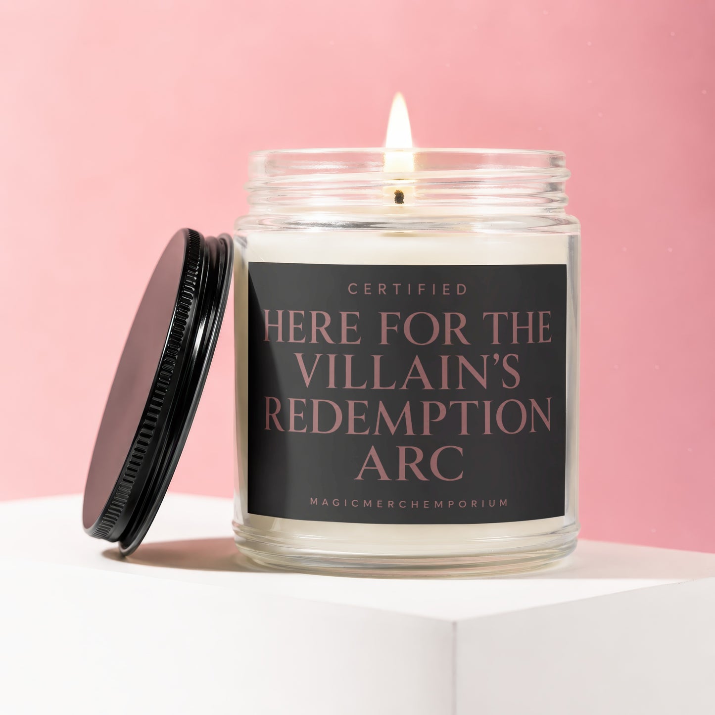Candle in glass jar with lid off, featuring text "CERTIFIED HERE FOR THE VILLAIN'S REDEMPTION ARC".