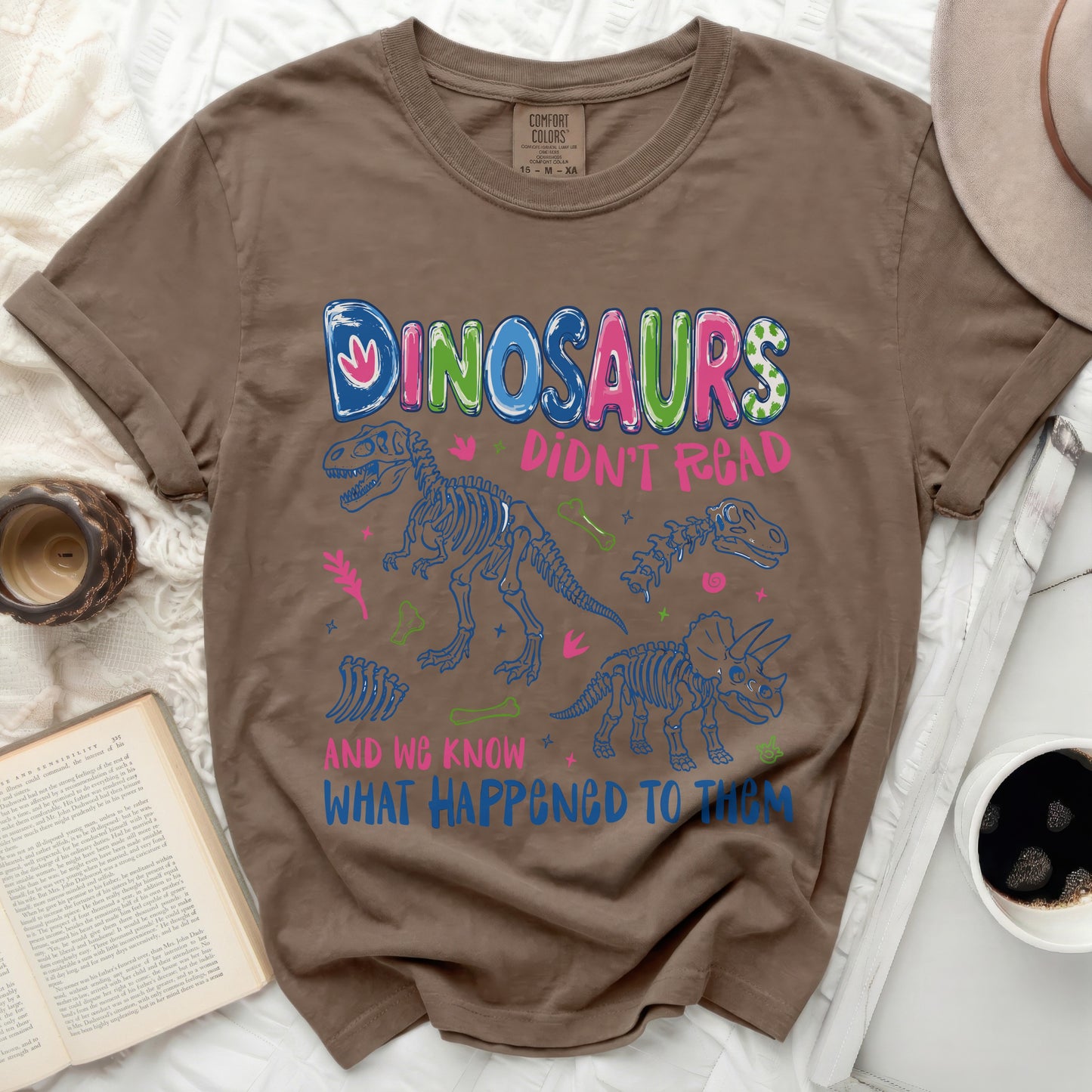 Brown t-shirt with dinosaurs saying "Dinosaurs Didn't Read and We Know What Happened To Them".