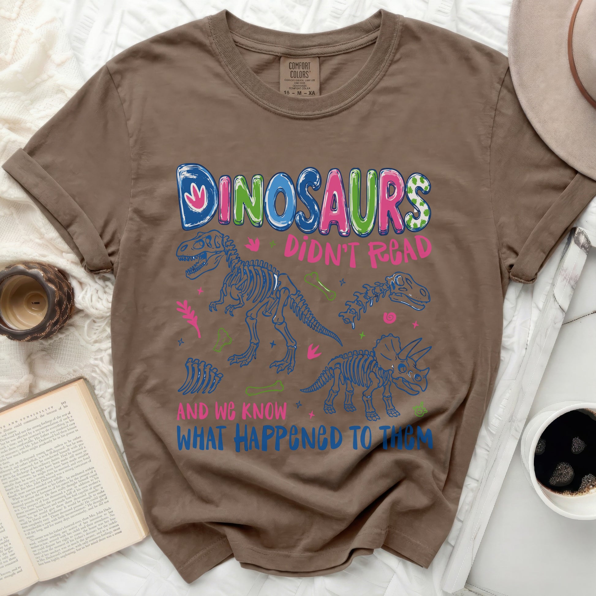 Brown t-shirt with dinosaurs saying "Dinosaurs Didn't Read and We Know What Happened To Them".