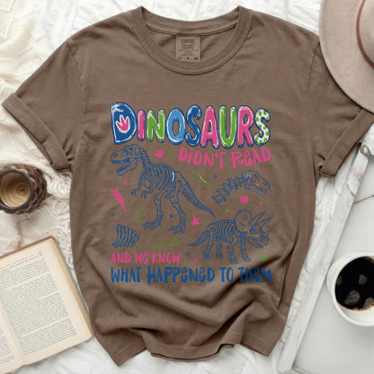 Brown t-shirt with dinosaurs saying "Dinosaurs Didn't Read and We Know What Happened To Them".
