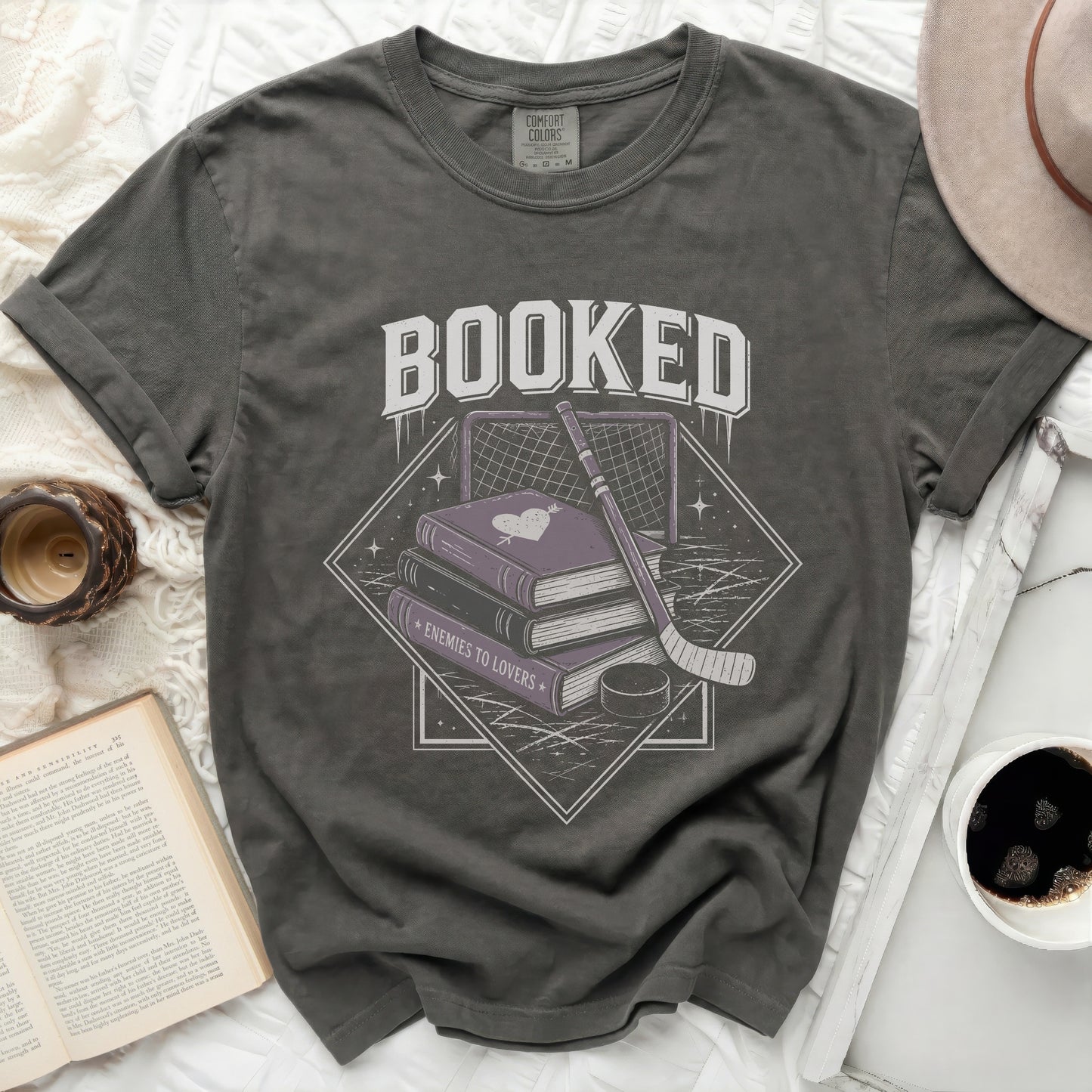 Book-themed graphic on a dark grey t-shirt with "Booked" and "Enemies to Lovers."
