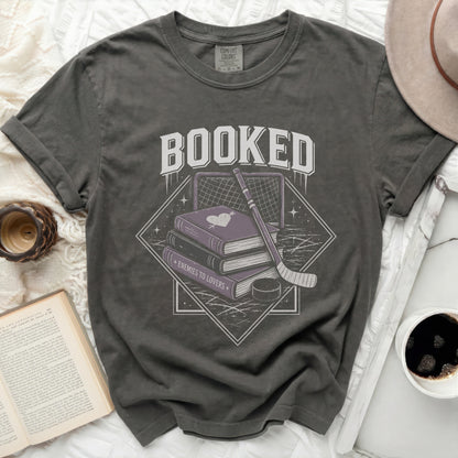Book-themed graphic on a dark grey t-shirt with "Booked" and "Enemies to Lovers."