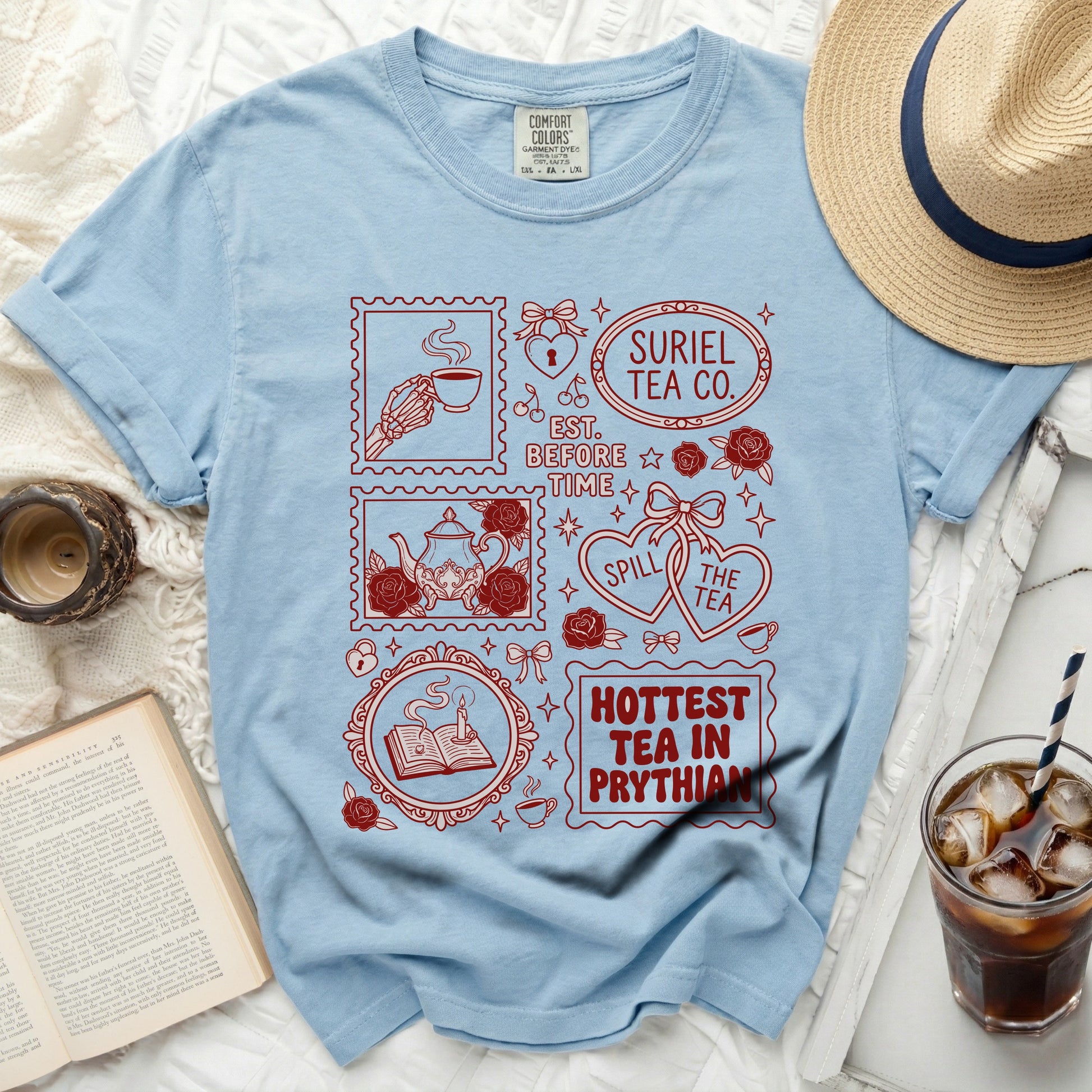 Light blue t-shirt with red graphics of stamps, teacups, and text.