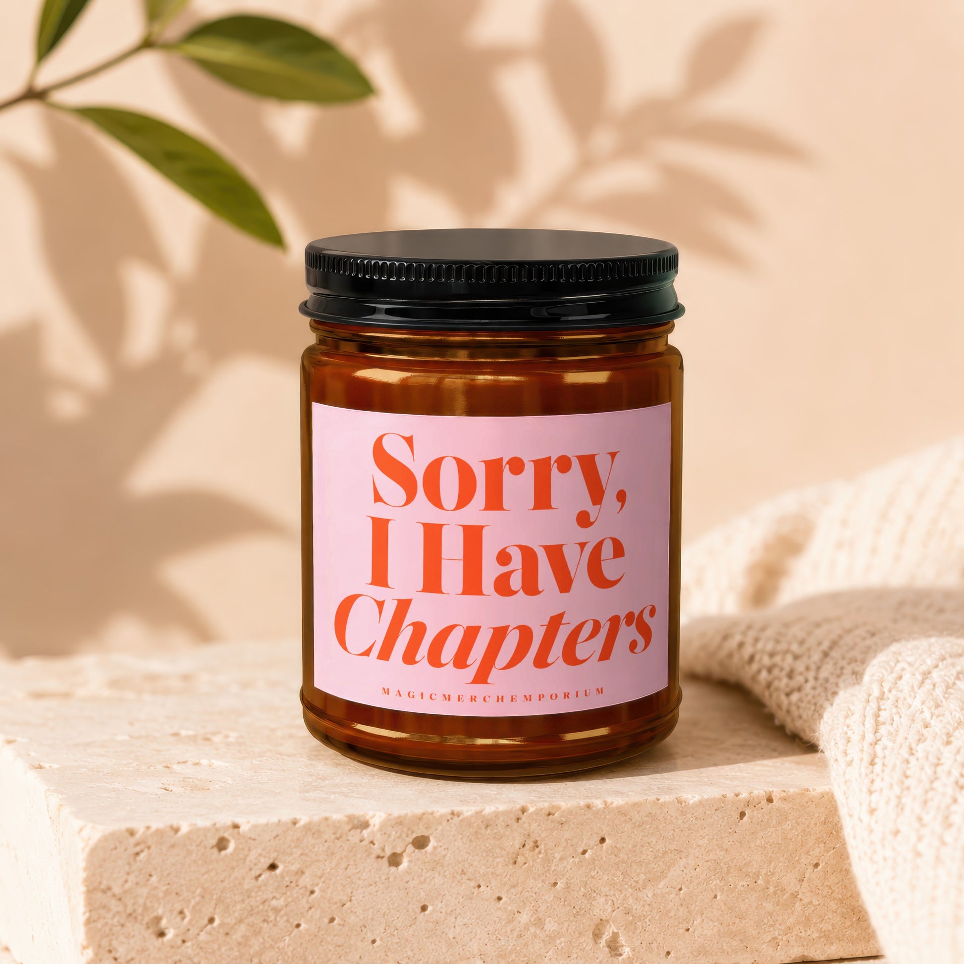 Amber jar candle with pink label reading "Sorry, I Have Chapters".