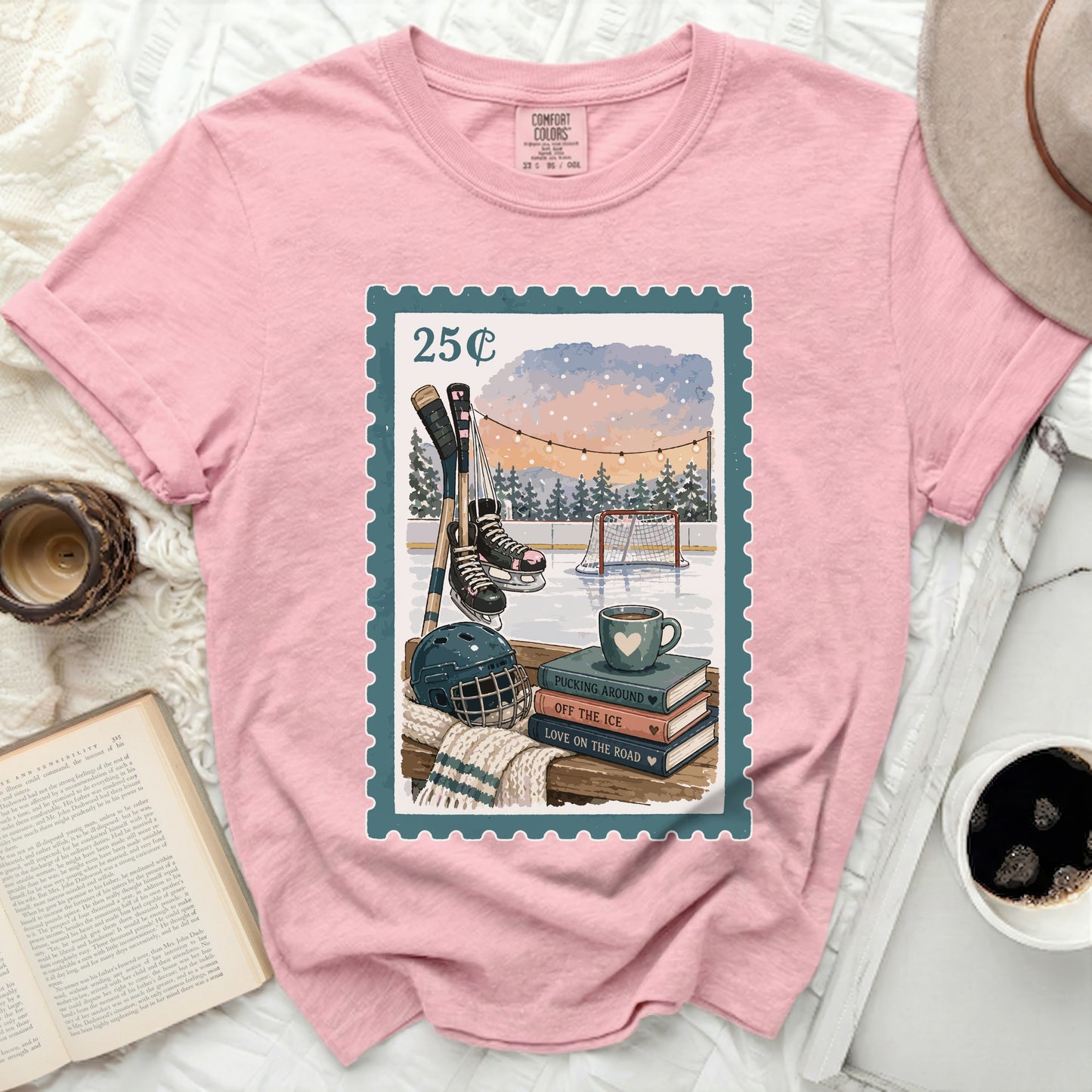 Pink t-shirt with postage stamp graphic featuring ice skates, hockey sticks, and a mug.