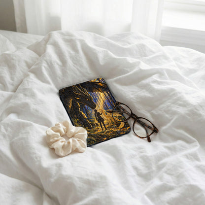 Book with dragon and forest art, scrunchie, and glasses on white bedding.
