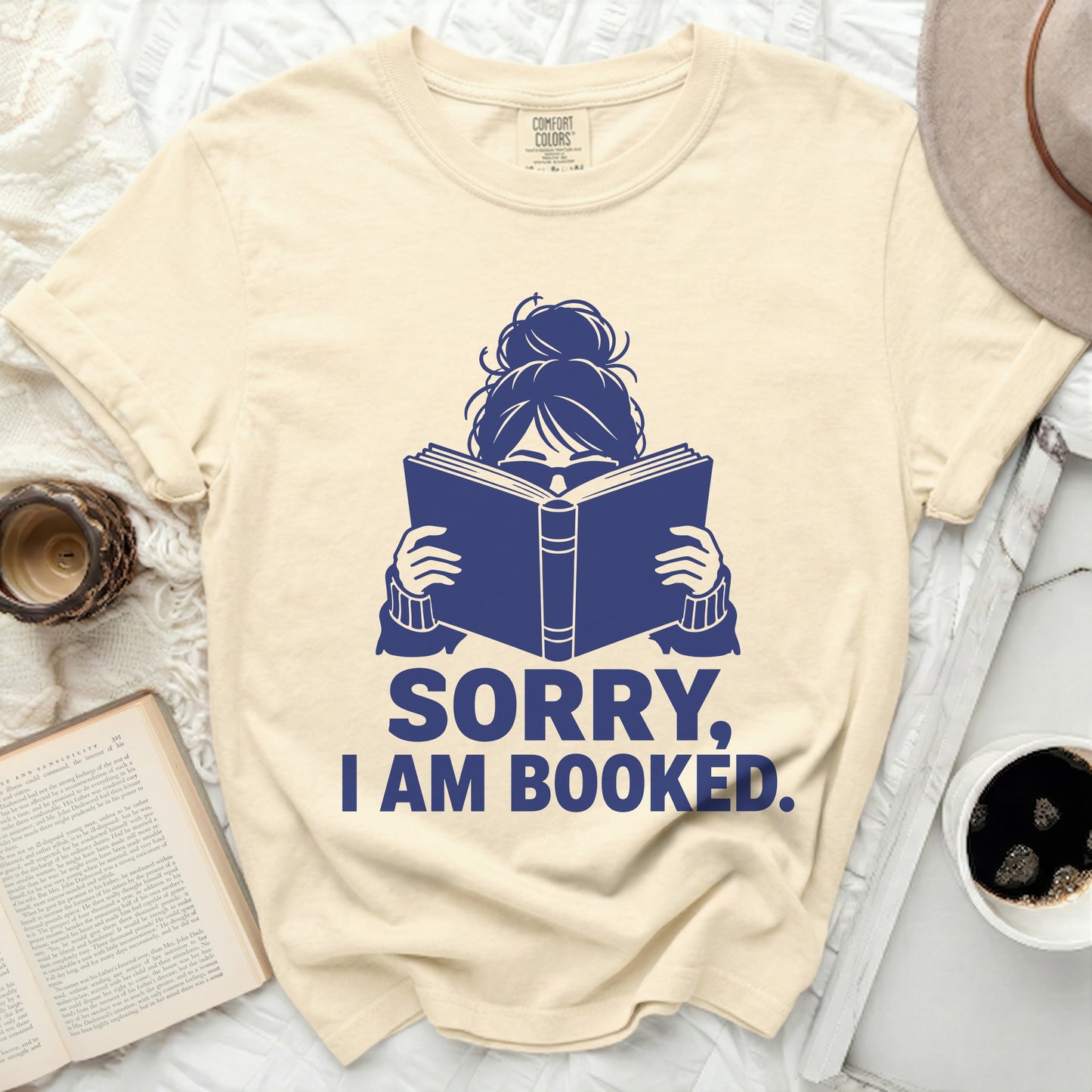 T-shirt with blue graphic of person reading a book, "SORRY, I AM BOOKED."