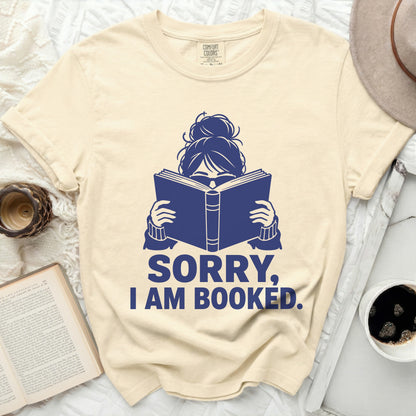T-shirt with blue graphic of person reading a book, "SORRY, I AM BOOKED."