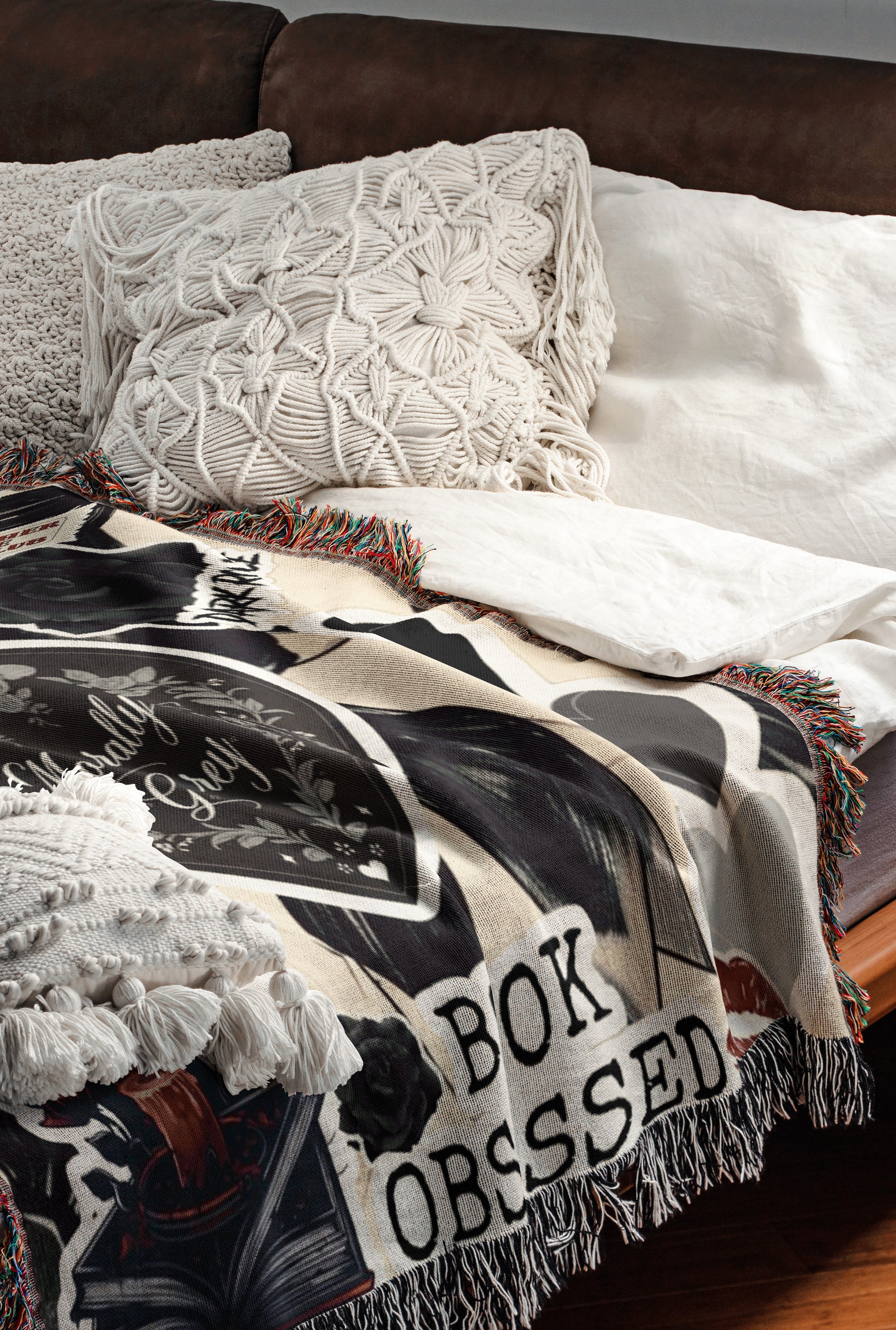 a cozy bedroom scene with a bed covered in a white comforter and a patterned throw blanket. The blanket has the text "BOK OBSESSION" printed on it.