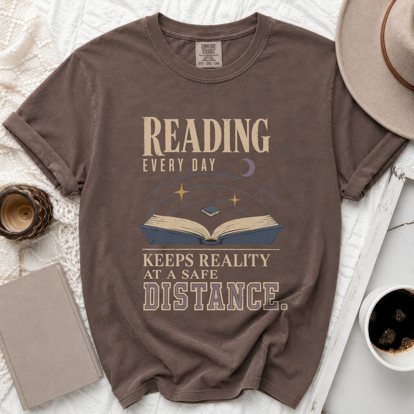 Brown t-shirt with "Reading Every Day Keeps Reality At A Safe Distance" text and book graphic.