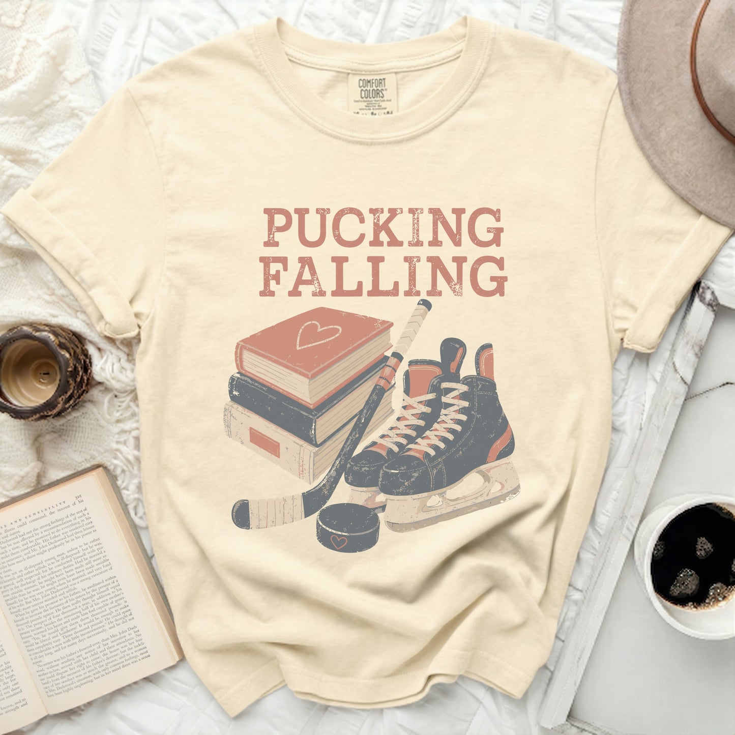 Cream t-shirt with "Pucking Falling" text and hockey gear illustration.