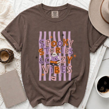 Brown t-shirt with "Spooky Stories & Cozy Vibes" text and Halloween graphics.