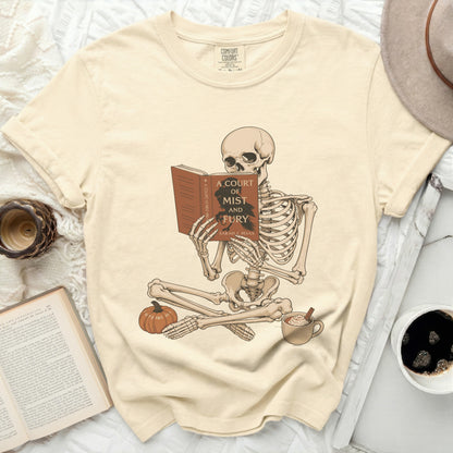 Skeleton reading "A Court of Mist and Fury" book with pumpkin and coffee.