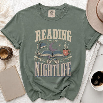 Green t-shirt with "Reading Is My Nightlife" graphic, open book, lamp, and mug.