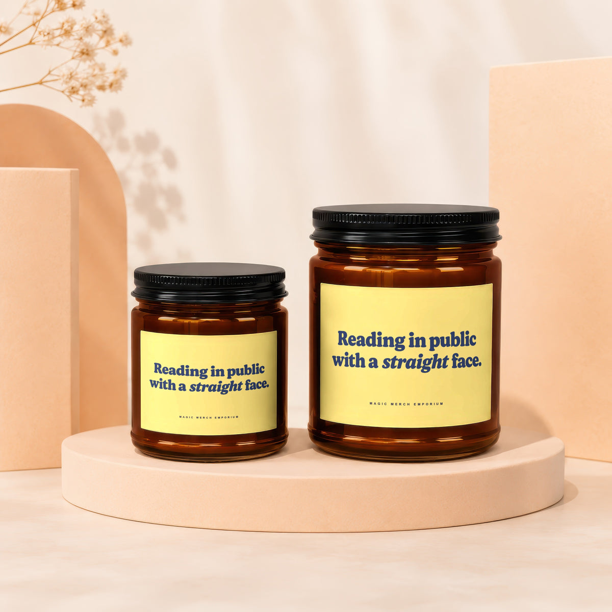 Two amber glass candles with black lids and yellow labels reading "Reading in public with a straight face."