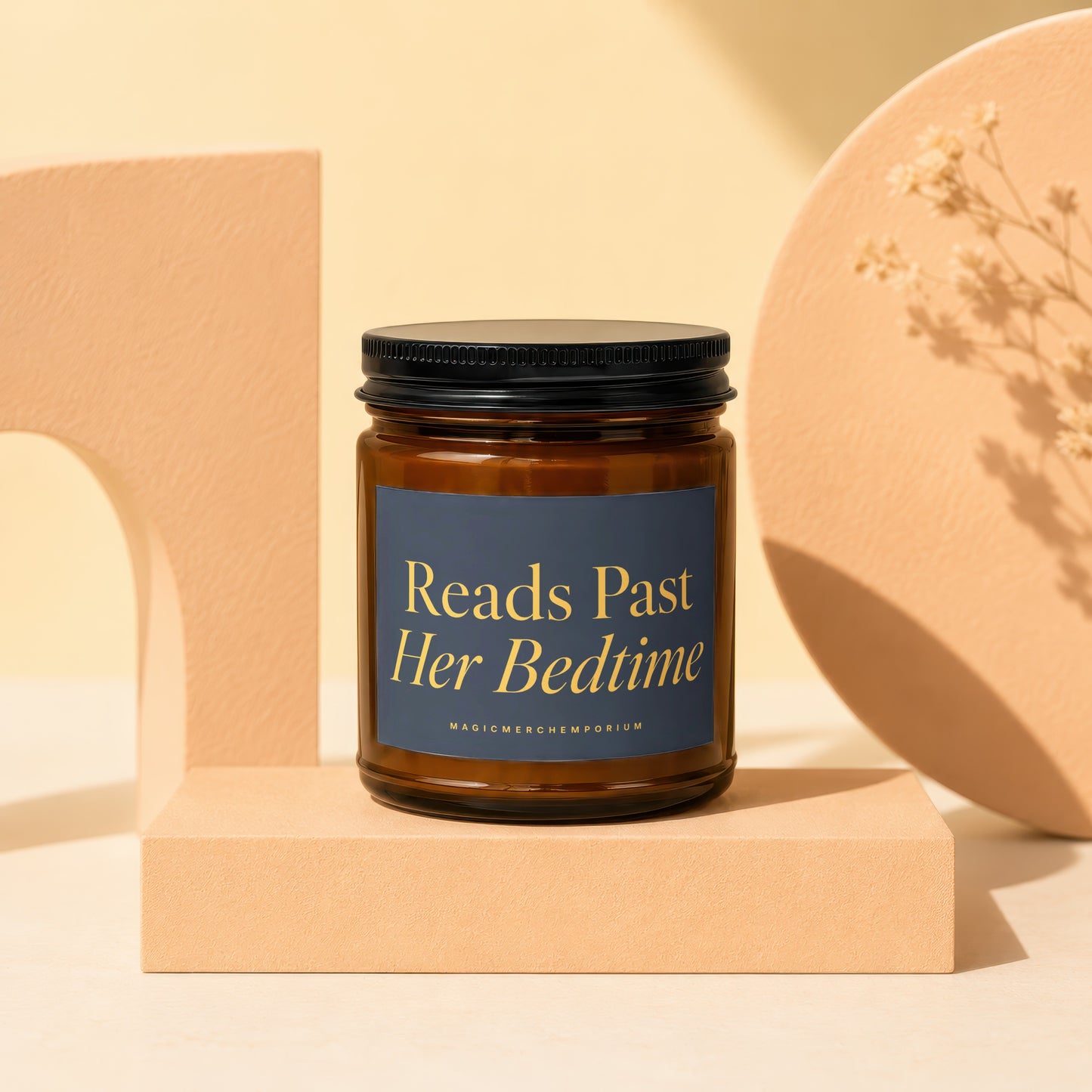 Amber glass candle with black lid and dark blue label reading "Reads Past Her Bedtime".