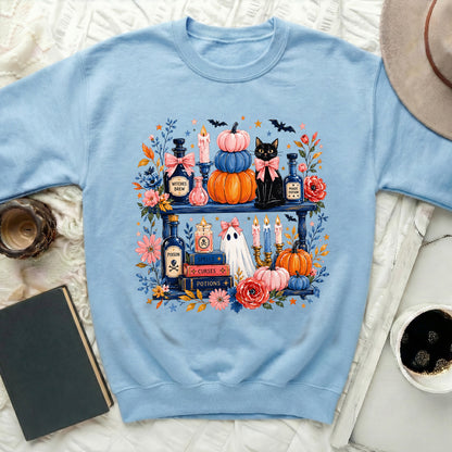 Light blue sweatshirt with Halloween-themed graphic of pumpkins, cat, ghost, and potions.