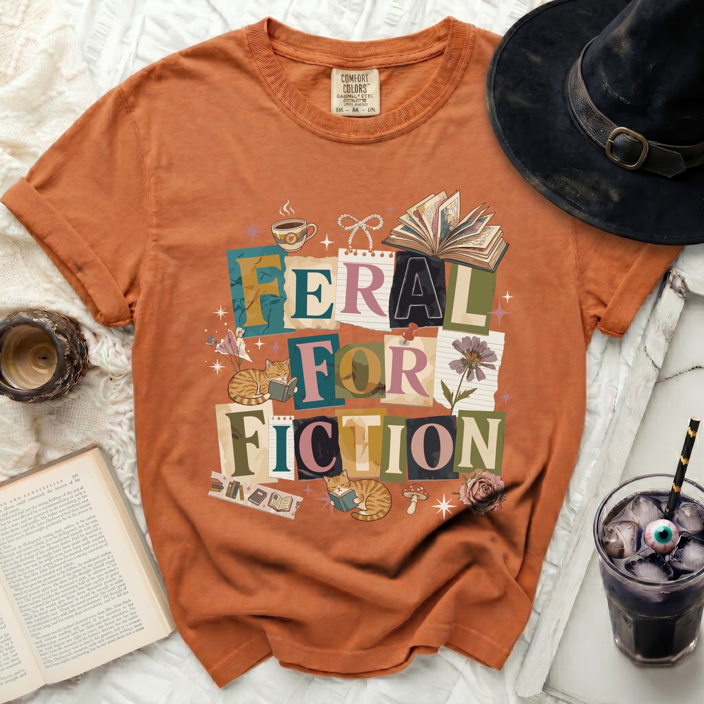 Orange t-shirt with "Feral For Fiction" graphic, featuring books, cats, and coffee.
