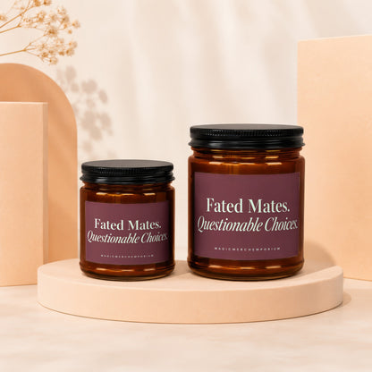 Two amber glass candles with dark lids and maroon labels that read "Fated Mates, Questionable Choices."