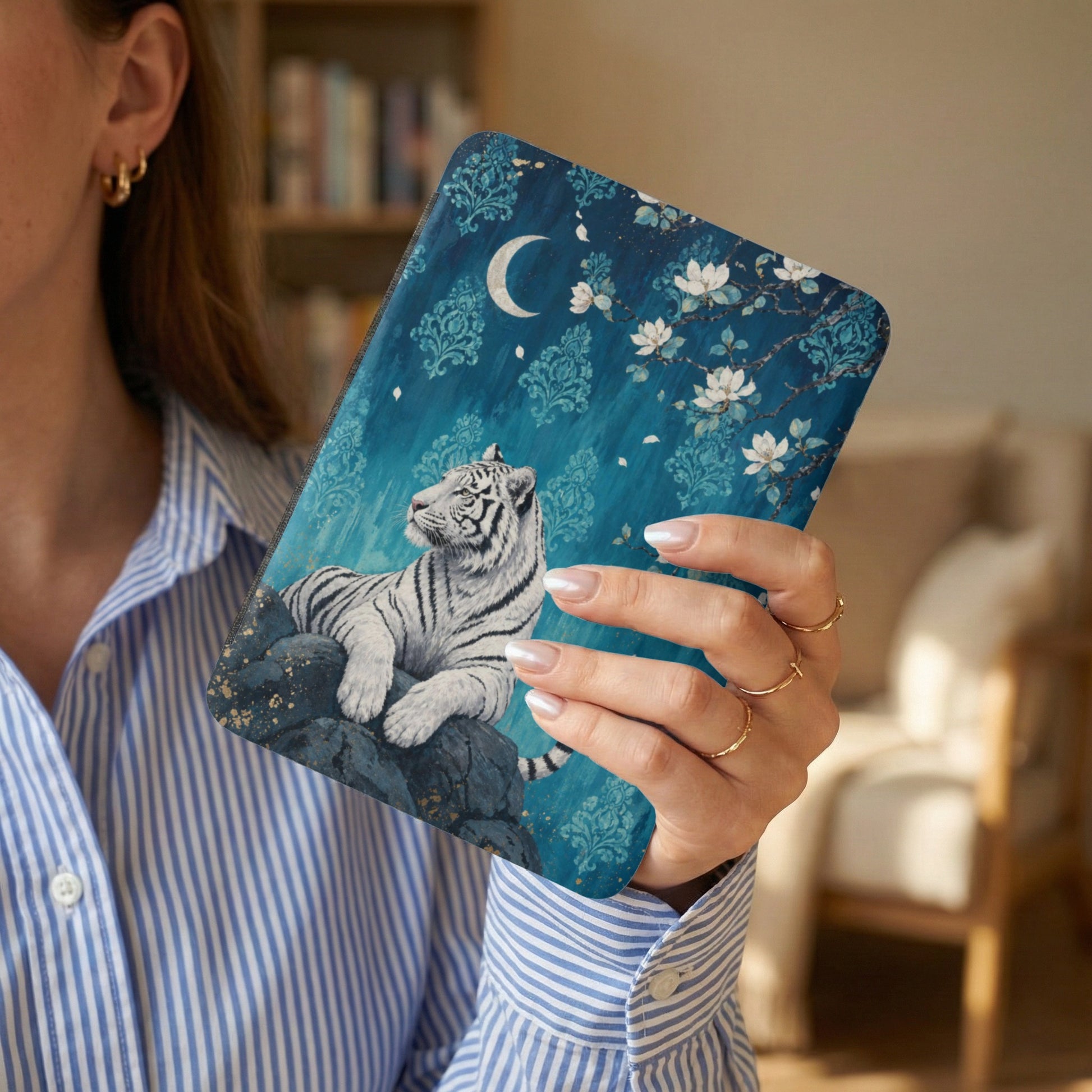 White tiger on blue floral and moon patterned cover held by a woman.