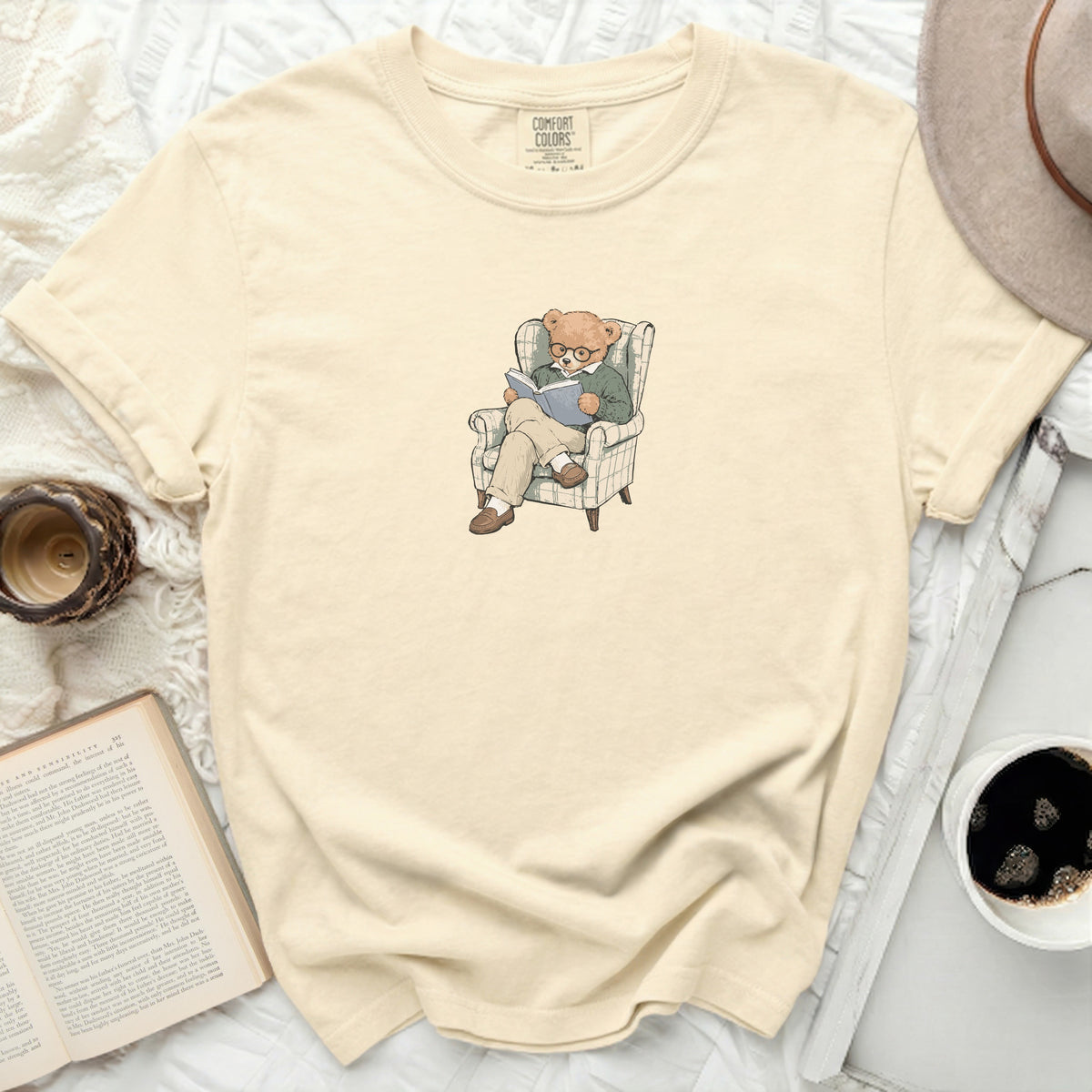 Cream t-shirt with illustration of a teddy bear reading in a chair.