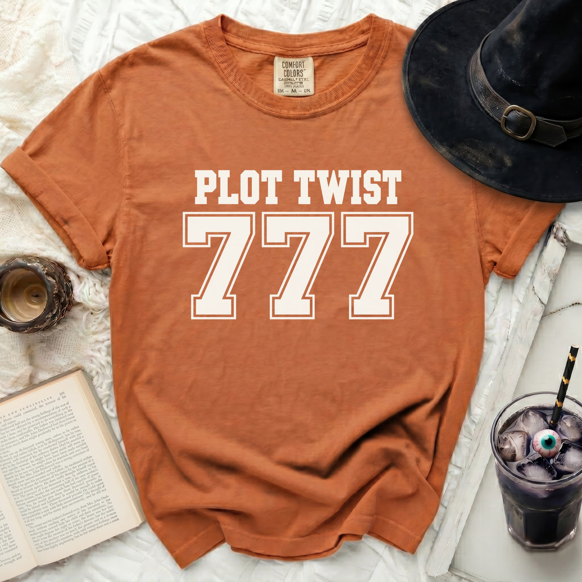 Orange t-shirt with white text "PLOT TWIST 777"