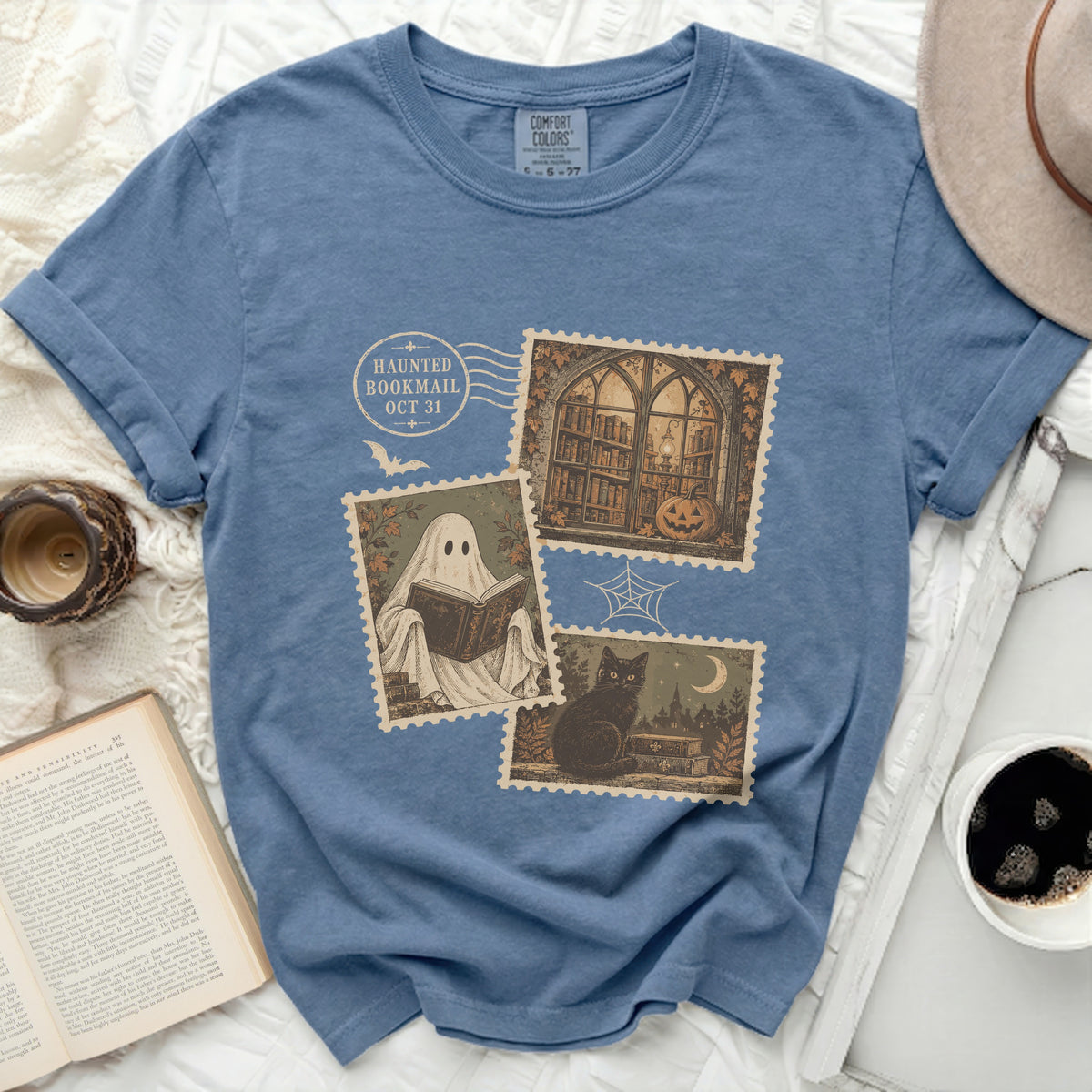 Blue t-shirt with Halloween-themed stamps: ghost reading, library, black cat.